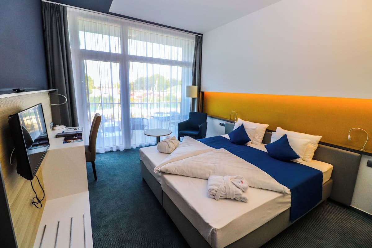 Una habitación de hotel con cama, escritorio, silla, mesita y ventana con vistas.
