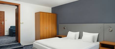 A hotel room with a large bed, a wardrobe, a bedside table, and a mirror.