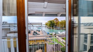 A balcony with a view of a marina, outdoor seating, and a pool.