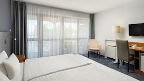 Une chambre d’hôtel avec un grand lit, un bureau, une chaise, une télévision et une vue sur l’extérieur.