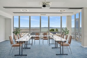 A conference room with a large table, chairs, and a view of the cityscape through large windows. - Hotel Yacht Wellness & Business (Siófok)