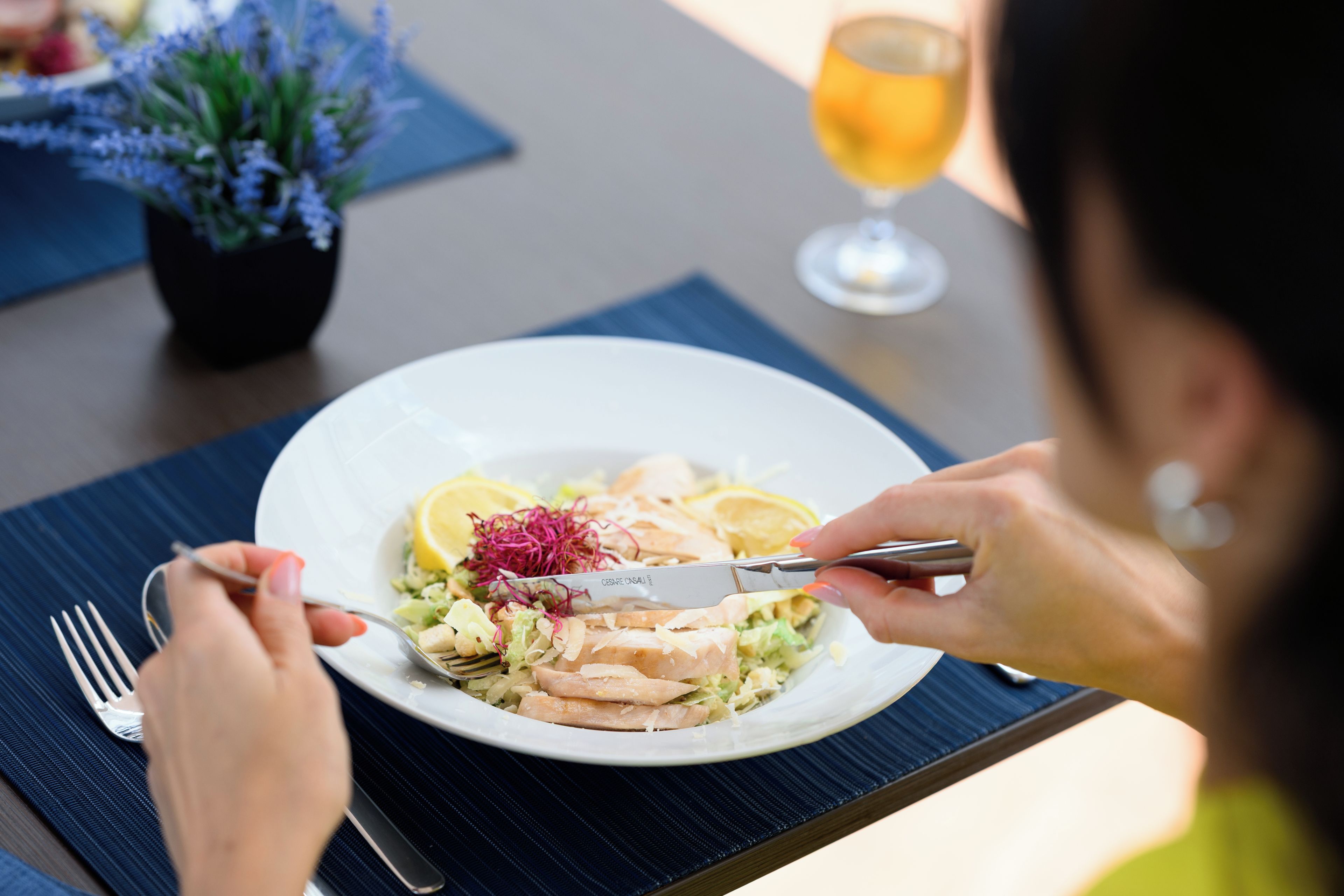 A dining table with a plate of food, a glass of drink, and a potted plant.