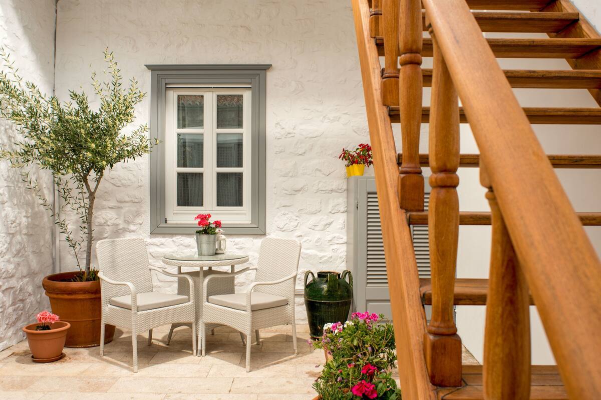 A white wicker chair and table set against a white wall with a window.
