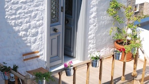 A white stone building with a wooden bench and potted plants on the porch. - Hydras Chromata (Hydra)