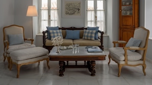 A living room with a sofa, two armchairs, a coffee table, and a cabinet. - Hydras Chromata (Hydra)