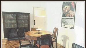 Un comedor con una mesa redonda, sillas, una lámpara y un cartel en la pared.