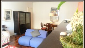 Una sala de estar con un sofá azul, una mesita, un armario y una planta.