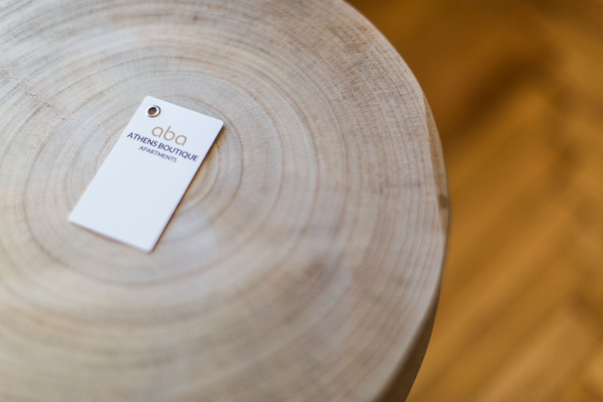 A white tag with the text 'aba' and 'ATHENS BOUTIQUE APARTMENTS' on a wooden surface.