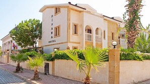 A building labeled "DINARA HOTEL" with a classic architectural style, featuring arched windows and a balcony. - Dinara Hotel (Kemer)