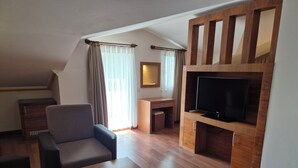 A modern living room with a flat-screen TV, wooden furniture, and a desk. - Dinara Hotel (Kemer)