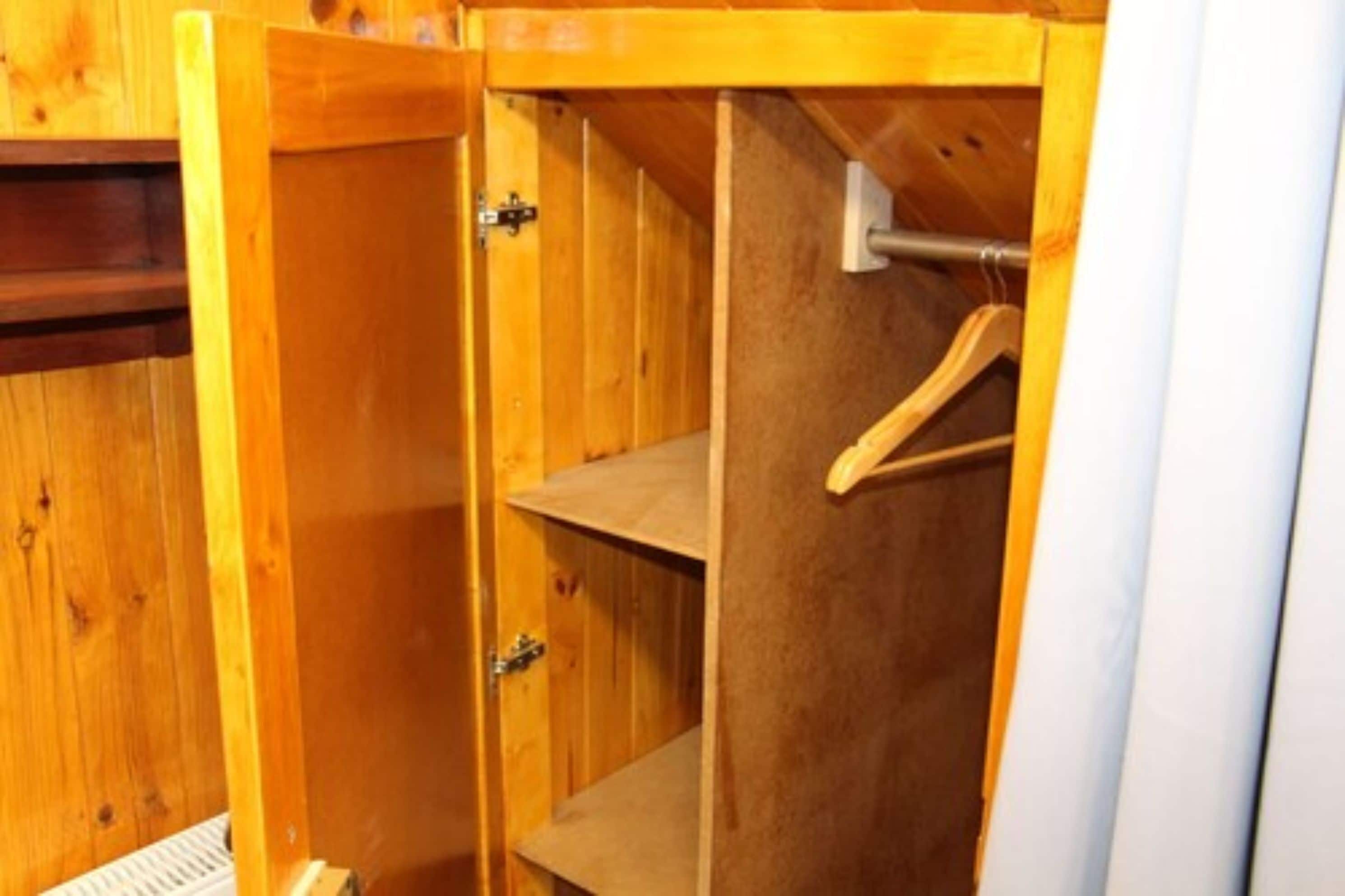 Un armario de madera con repisas y una barra para colgar.
