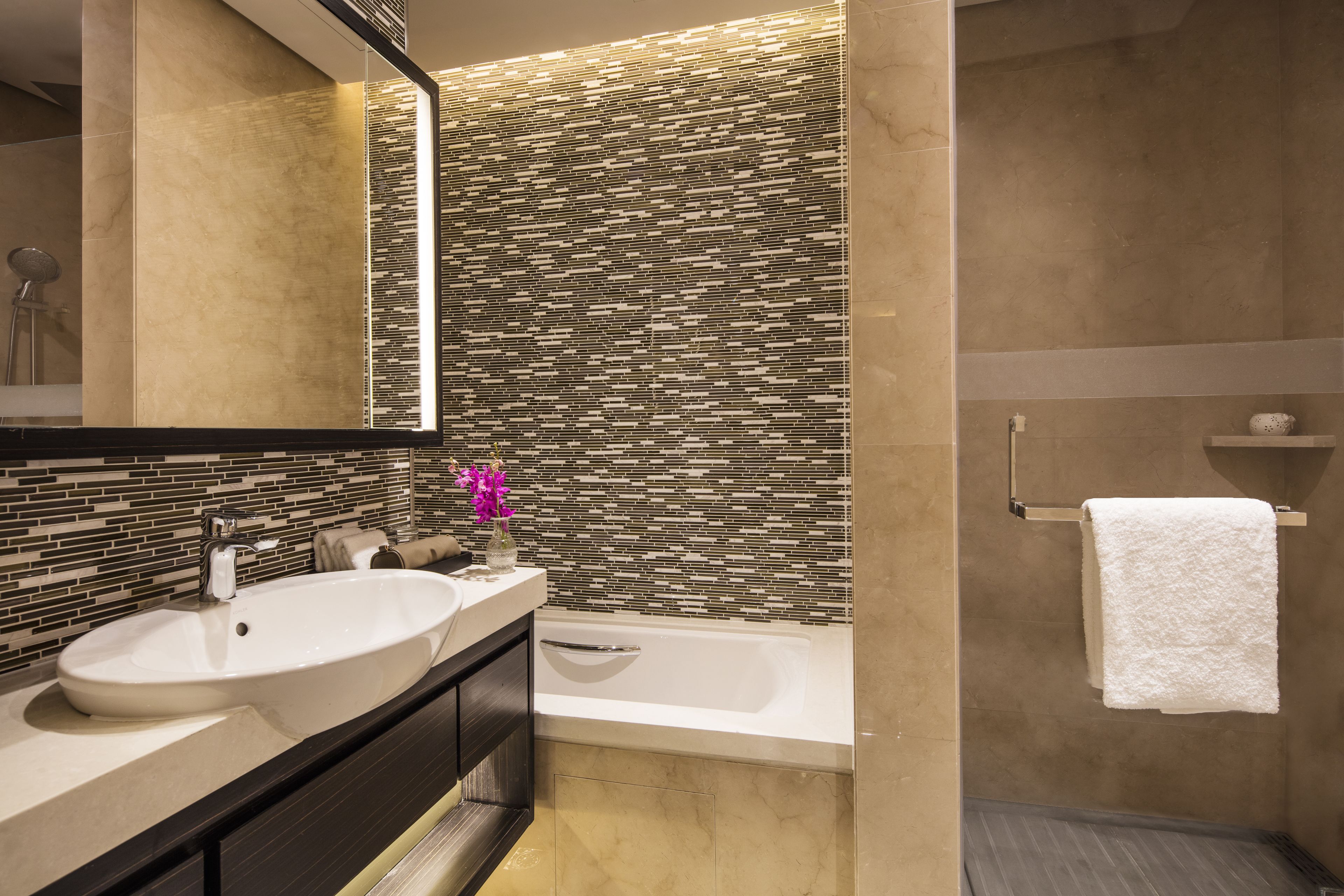 Une salle de bain moderne avec un grand lavabo, un miroir, une baignoire et un mur recouvert de carreaux.