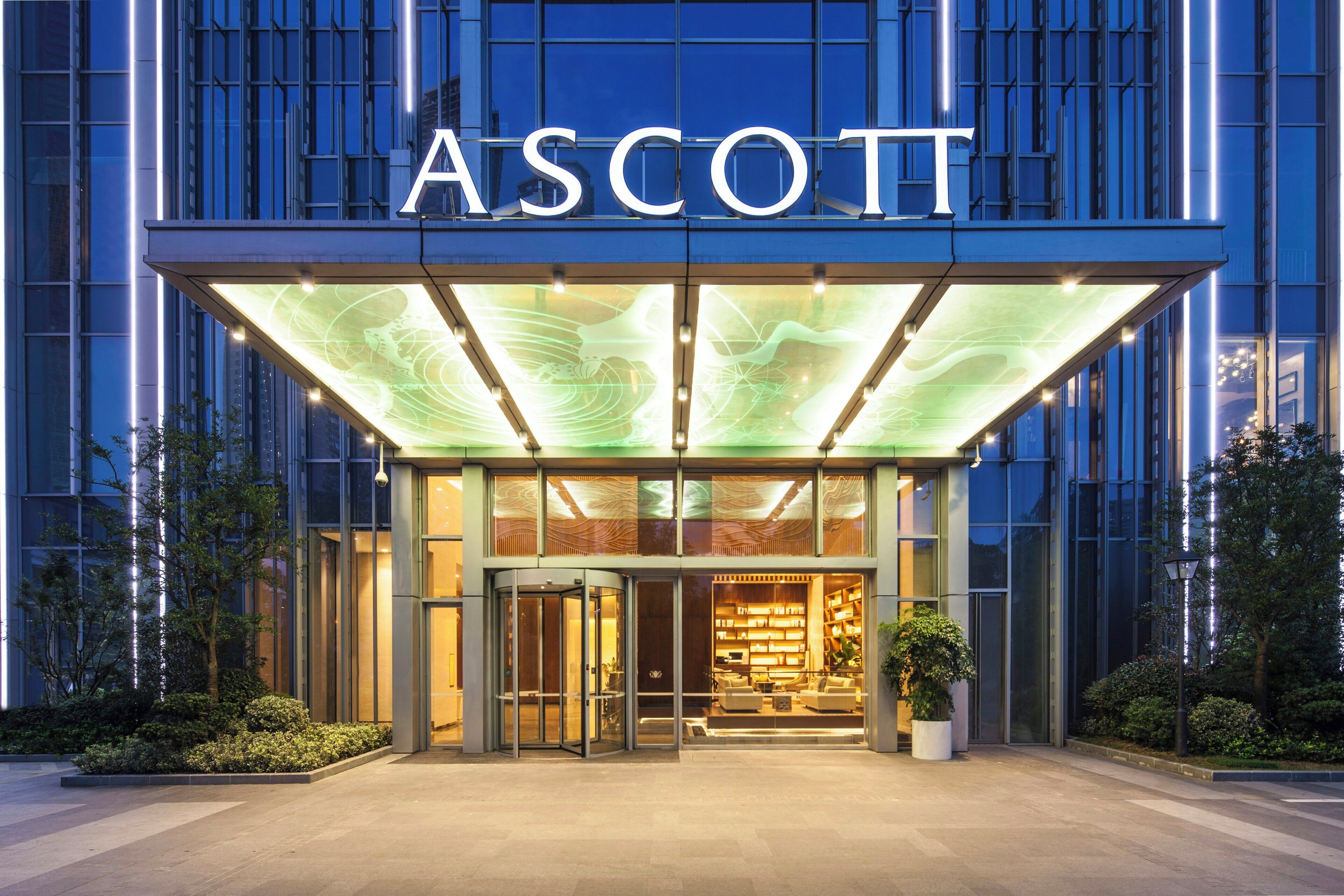 A hotel entrance with a glass facade, a rotating door, and a well-lit interior visible through the glass.