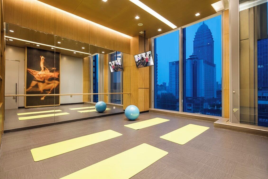 A gym with exercise mats, a mirrored wall, and a cityscape view.
