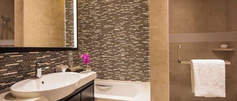 Un baño moderno con un lavamanos grande, una bañera y un espejo.