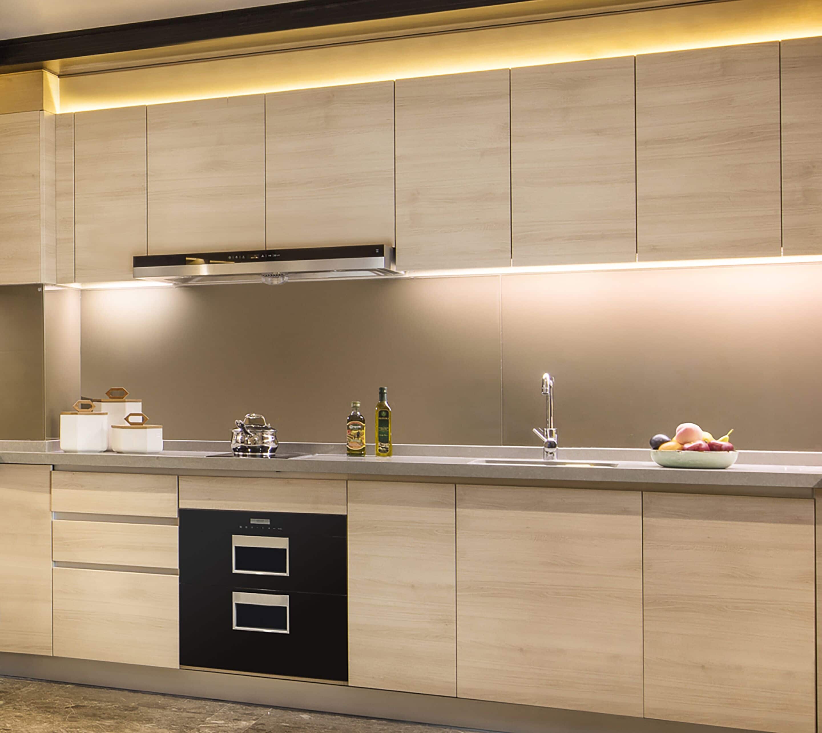 A modern kitchen with wooden cabinets, a stainless steel range hood, a built-in dishwasher, and a fruit bowl on the counter.