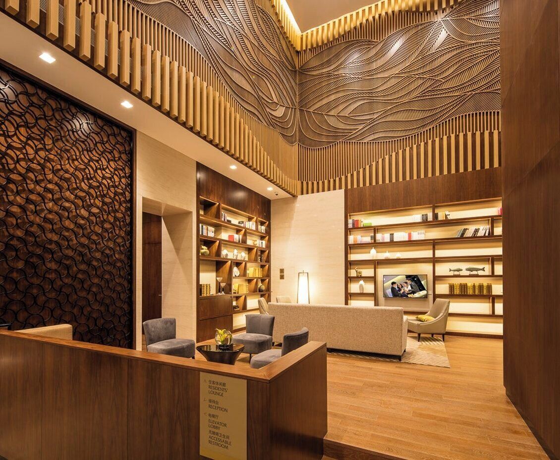 A hotel lobby with a reception desk, seating area, and bookshelves.