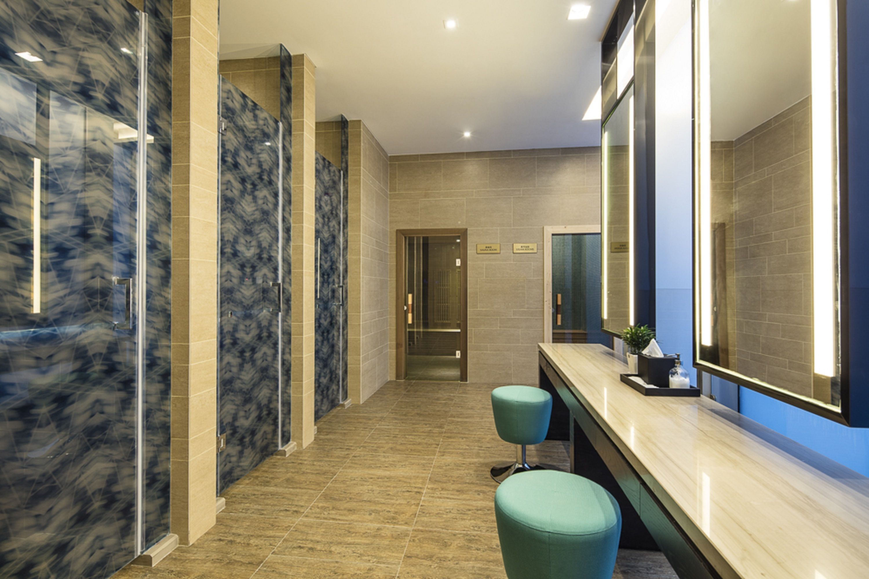 A modern hotel lobby with marble walls, a reception desk, and a glass-enclosed shower area.