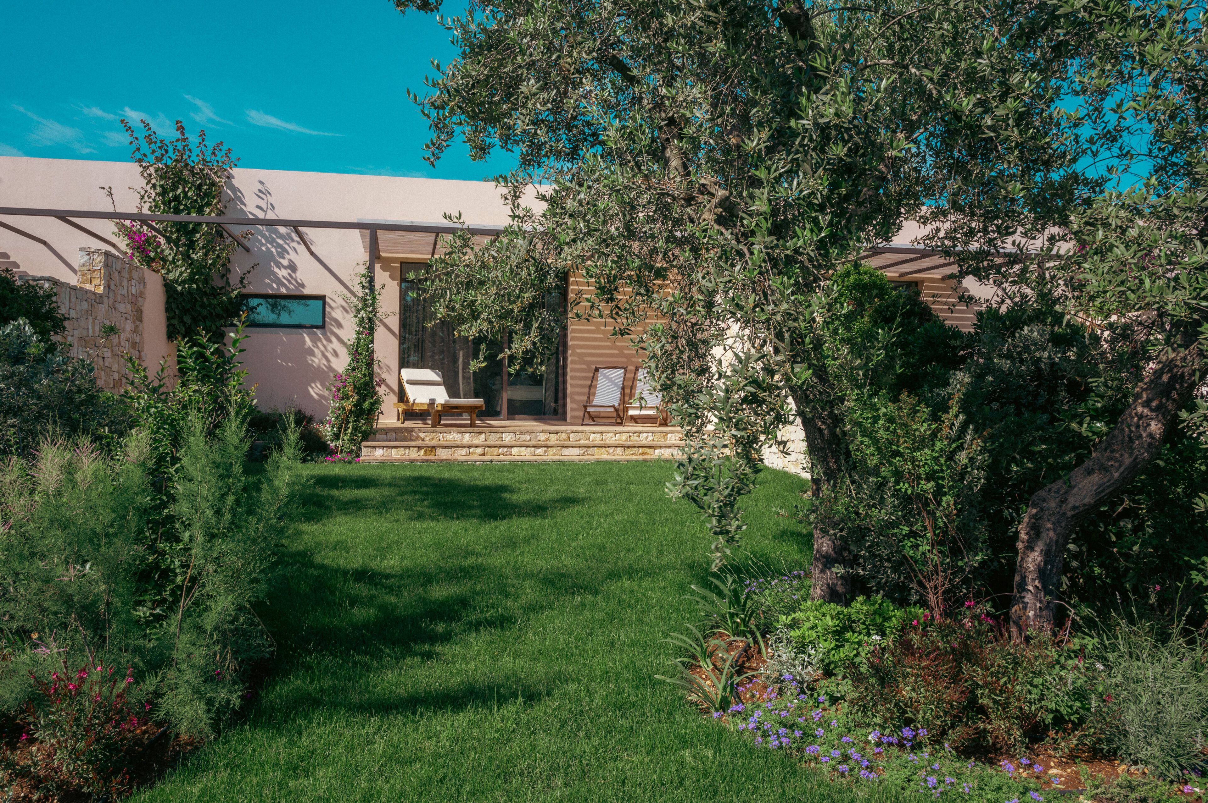 A garden with a patio area, stone walls, and various plants.