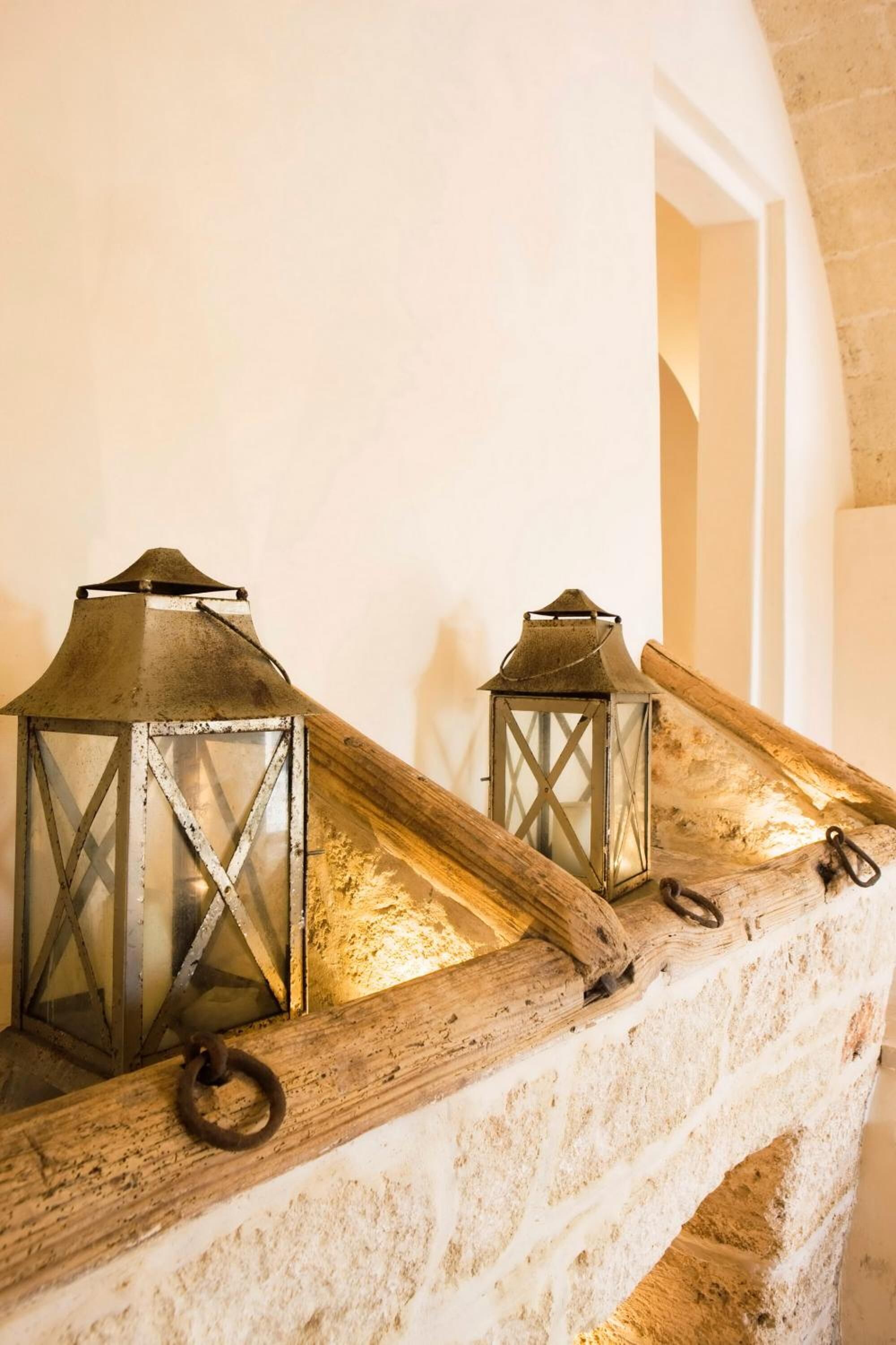 Two lanterns on a rustic wooden ledge against a stone wall.