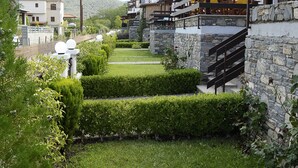 Un barrio residencial con muros de piedra, un césped cuidado y una escalera que lleva a un balcón.