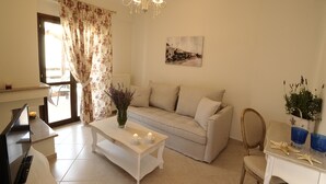Una sala de estar con sofá, mesa de centro, televisor y candelabro.