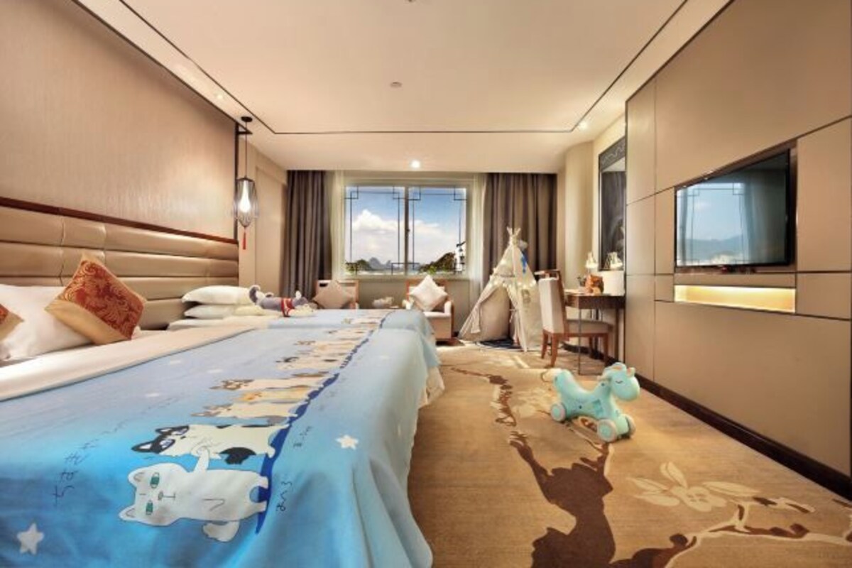 A hotel room with a large bed, a desk, a chair, a television, and a window with a view.