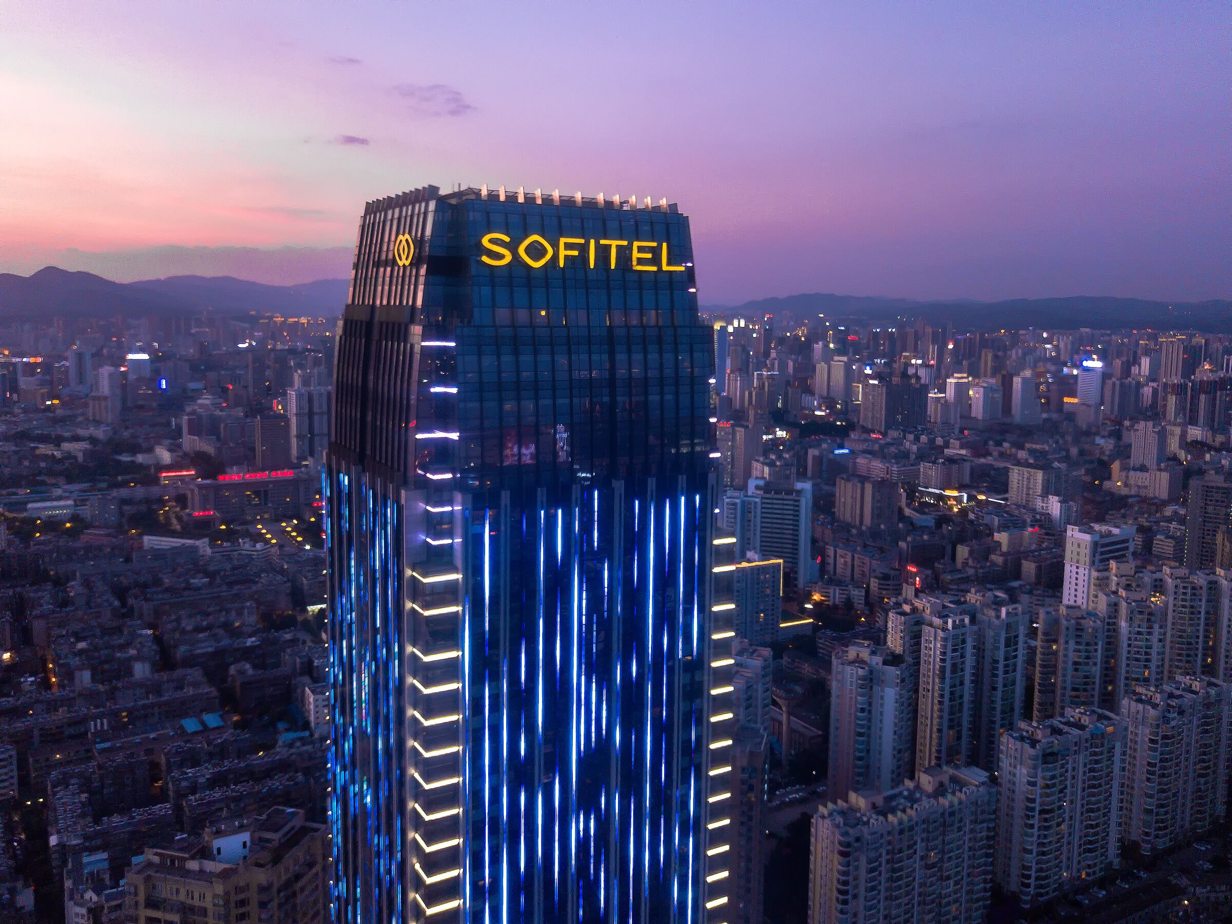 A high-rise building with the name "SOFITEL" illuminated on the top.