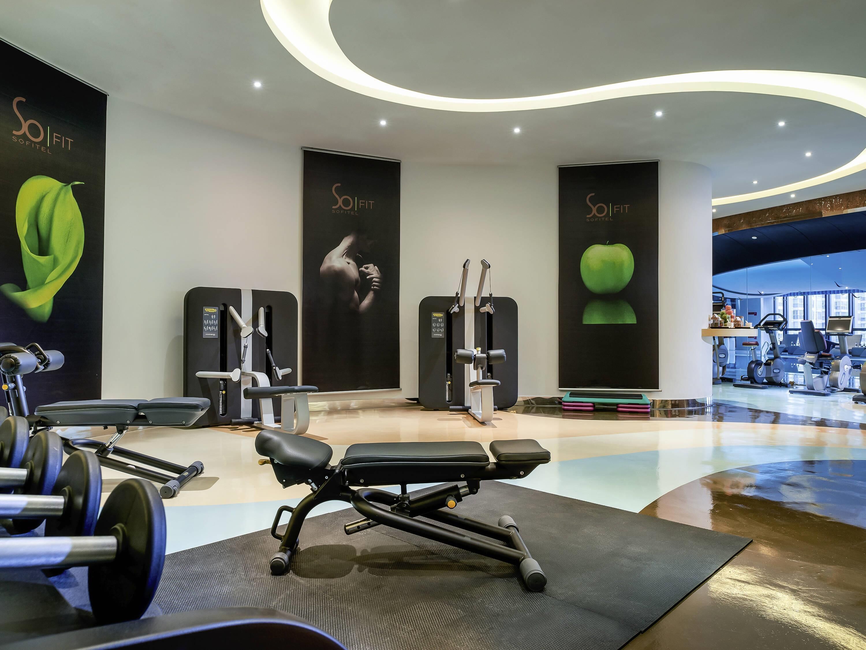 Une salle de sport moderne, dotée d’appareils d’exercice, de grandes affiches et d’un aménagement spacieux.