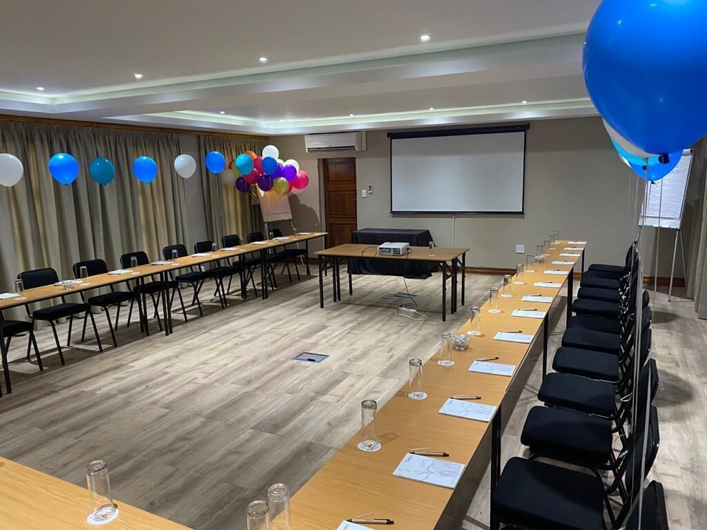 A conference room with long tables, chairs, a projector screen, and a screen for presentations.