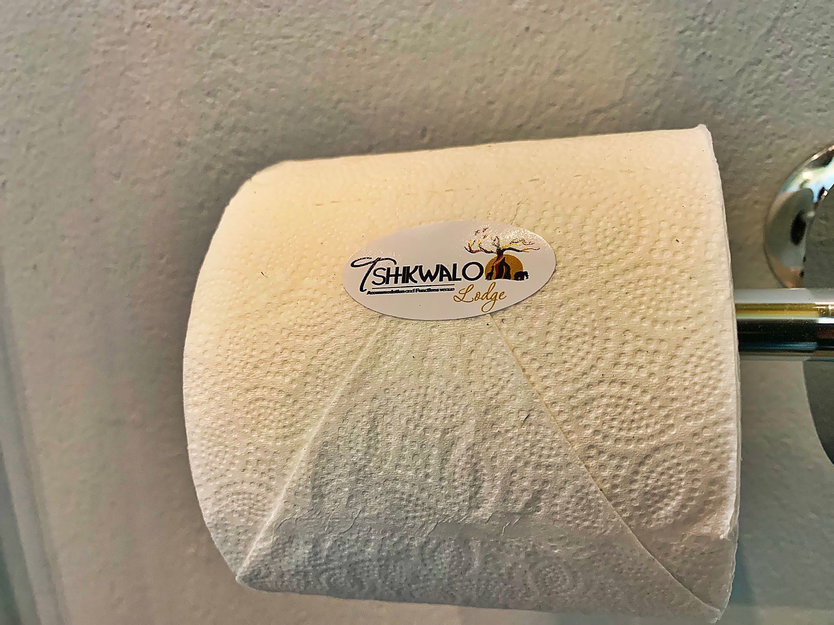 A toilet paper roll with a logo and text indicating it is from TSHKWALO Lodge.