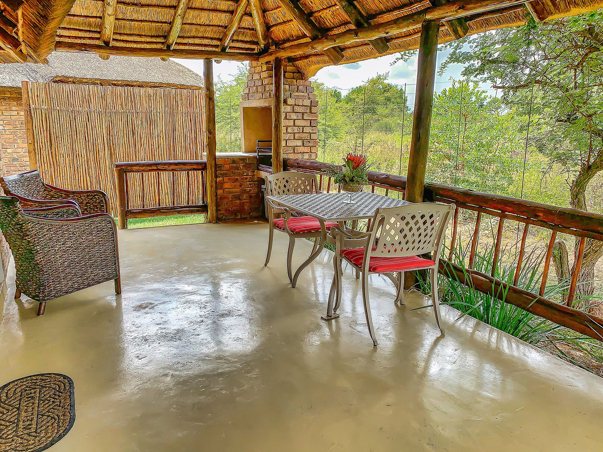 Un patio al aire libre con techo de paja, muebles de mimbre y vistas a zonas verdes.