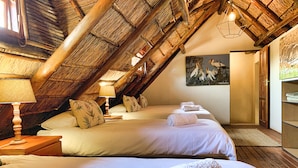 Una habitación con dos camas, techo de madera, un cuadro de pájaros y un armario de madera.