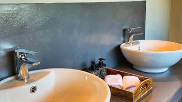 A bathroom with two white sinks, a dark countertop, and two ornate mirrors.