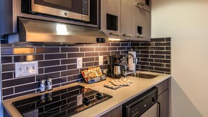 Eine moderne Küche mit Mikrowelle aus Edelstahl, Backofen, Kaffeemaschine und Geschirrspüler.
