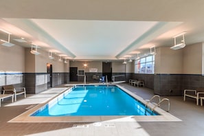 Una piscina interior con carriles delimitados, señales de seguridad y suelo de baldosas.
