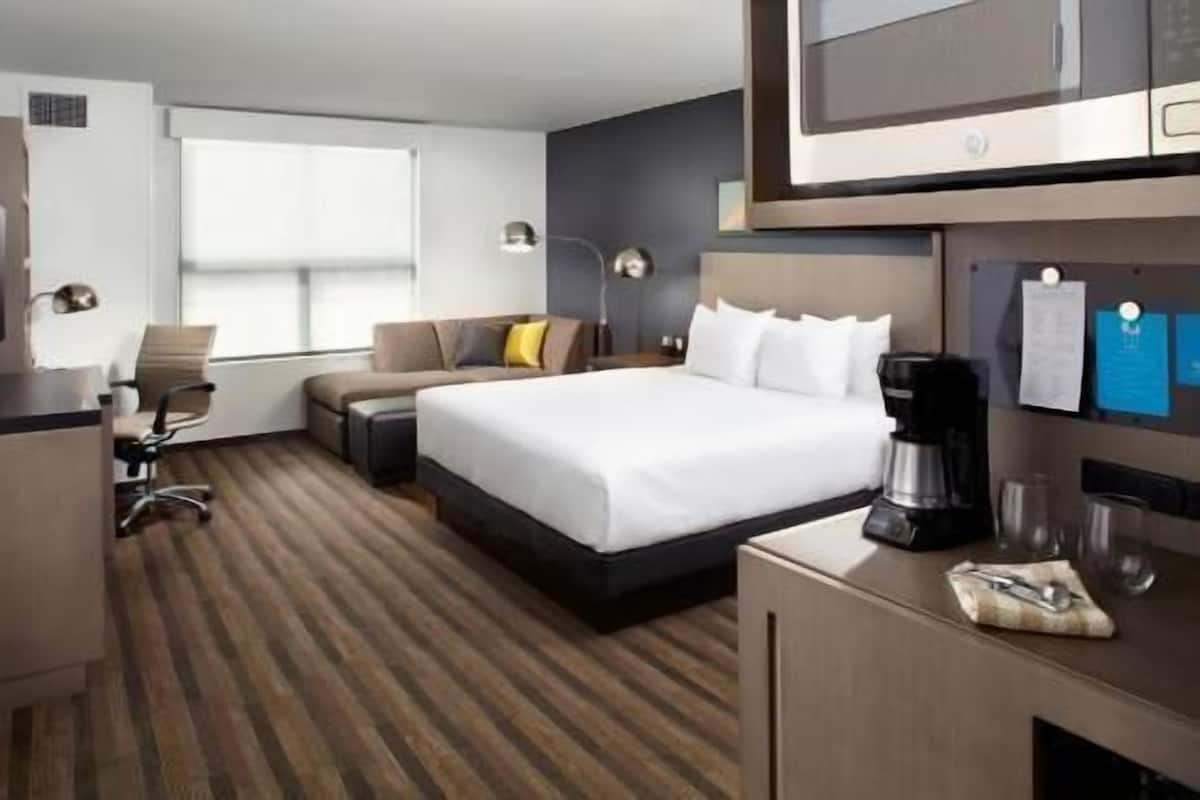Habitación de hotel con cama, escritorio, silla y televisor.