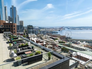 Terraço no telhado com área de estar externa, vista para o horizonte urbano e para a orla marítima.