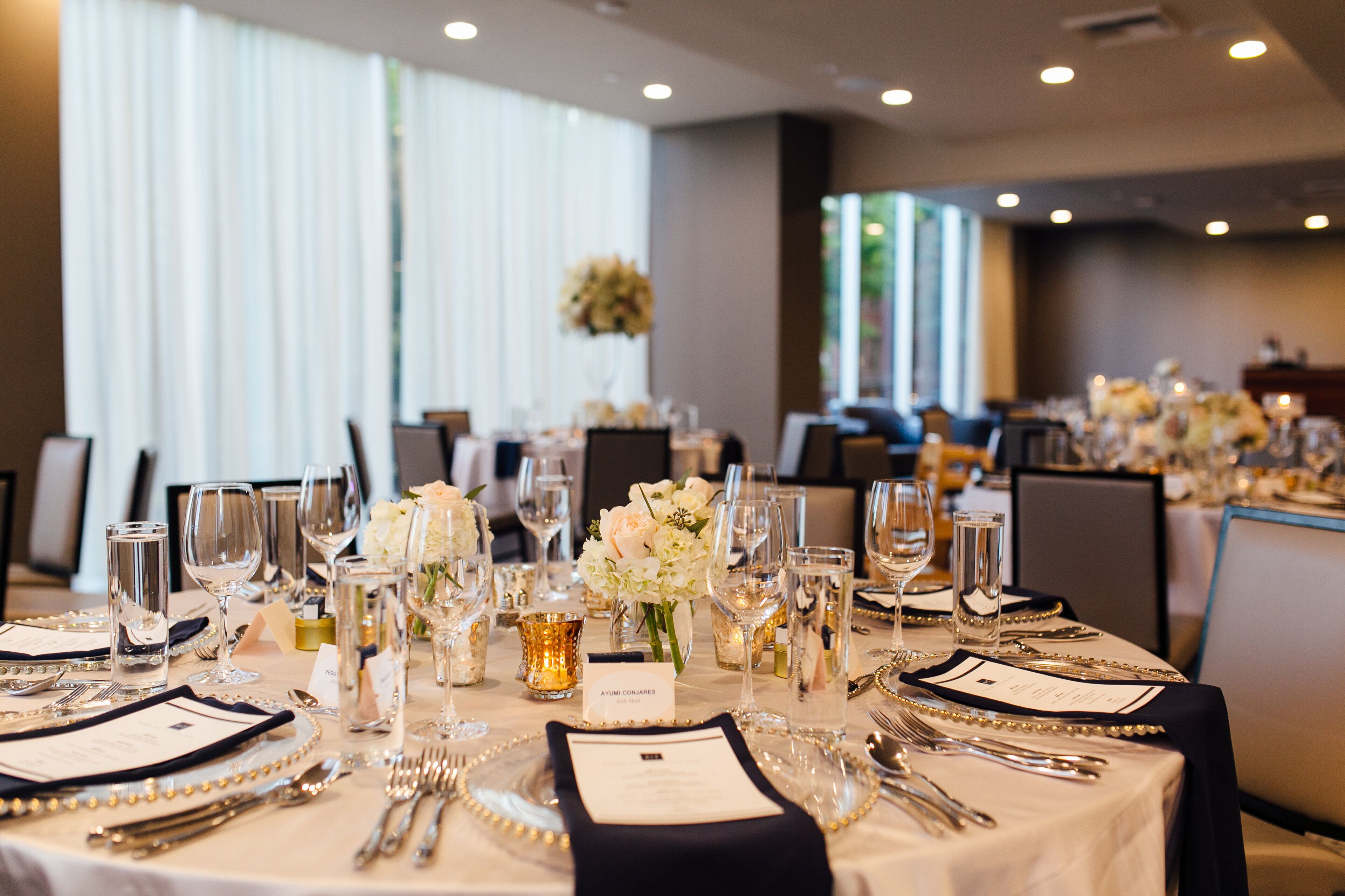 A banquet table set for a formal event with multiple place settings, glasses, and a centerpiece.