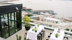 A rooftop terrace with a view of the sea, a Ferris wheel, and a pier. - Thompson Seattle, by Hyatt (Seattle)