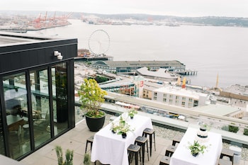 A bedroom with a large window offering a view of the sea and a distant island. at Thompson Seattle, by Hyatt