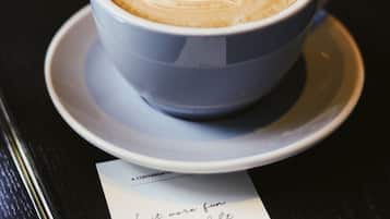 Una taza de café con arte de latte sobre un plato, colocada sobre una mesa con un menú.