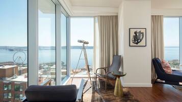 A modern living room with a large window offering a view of the sea and a Ferris wheel.