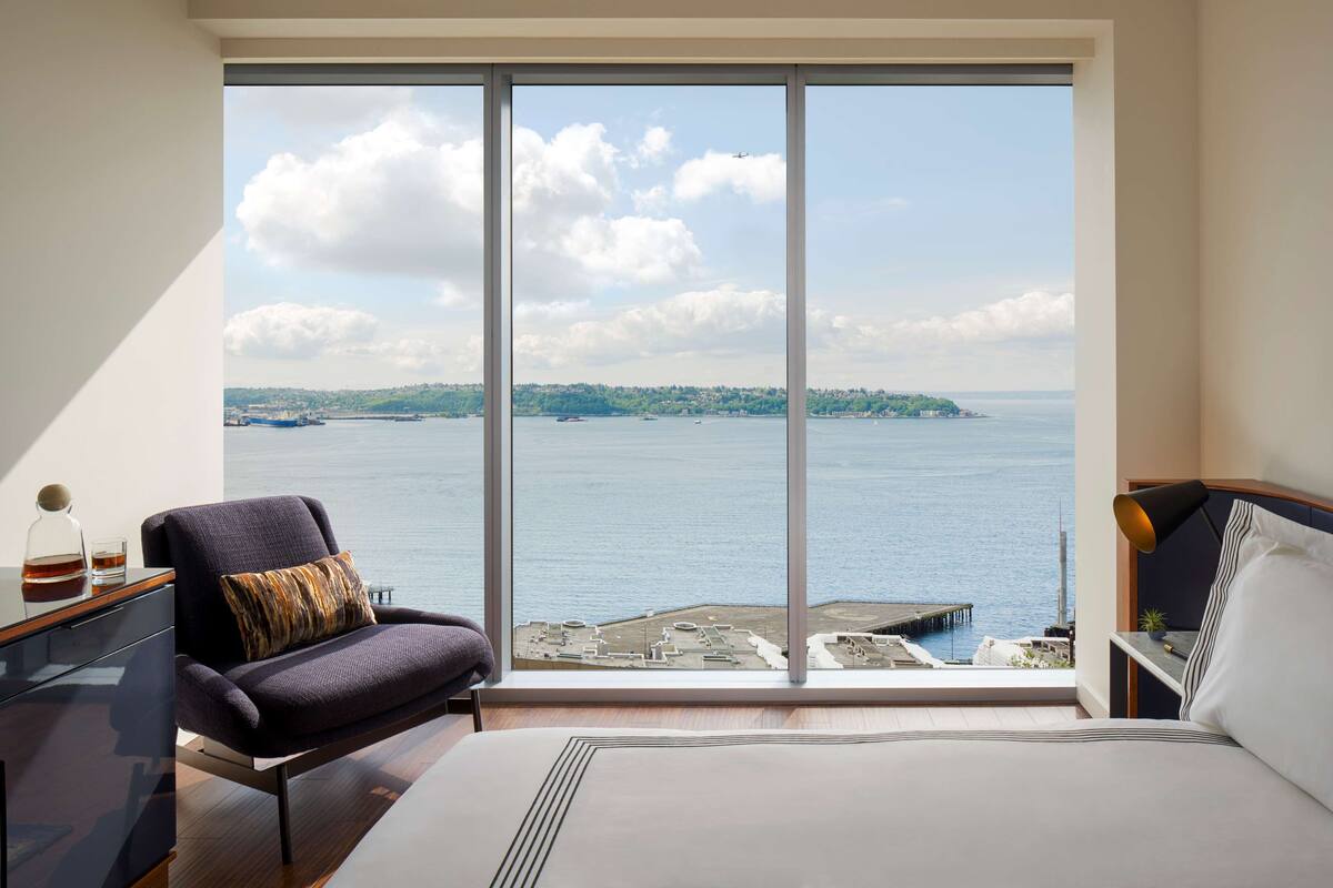 Quarto com uma janela grande que oferece vista para o mar e uma ilha distante.