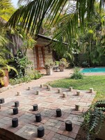 A courtyard with a pool, surrounded by lush greenery and a stone building with a wooden door.