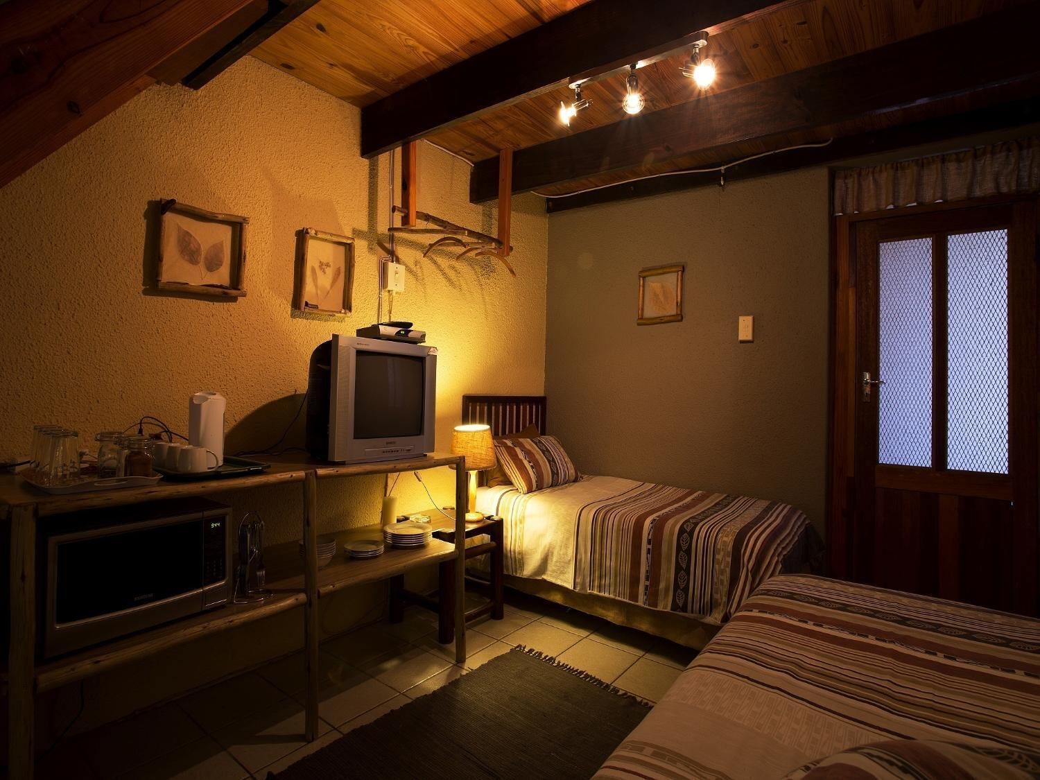 A cozy room with a bed, a television, and a small table with a lamp.