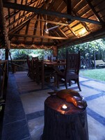 An outdoor dining area with wooden furniture and a thatched roof.