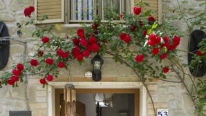 A stone building entrance with a wooden door, a staircase, and two large vases with plants. - B&B Villa Filetta (Roccafluvione)