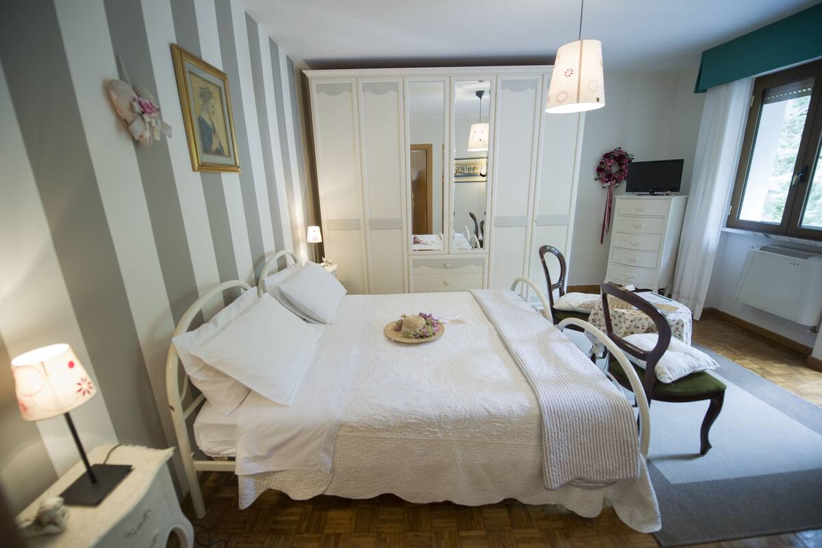 A neatly arranged bedroom with a bed, bedside tables, a wardrobe, and a television.
