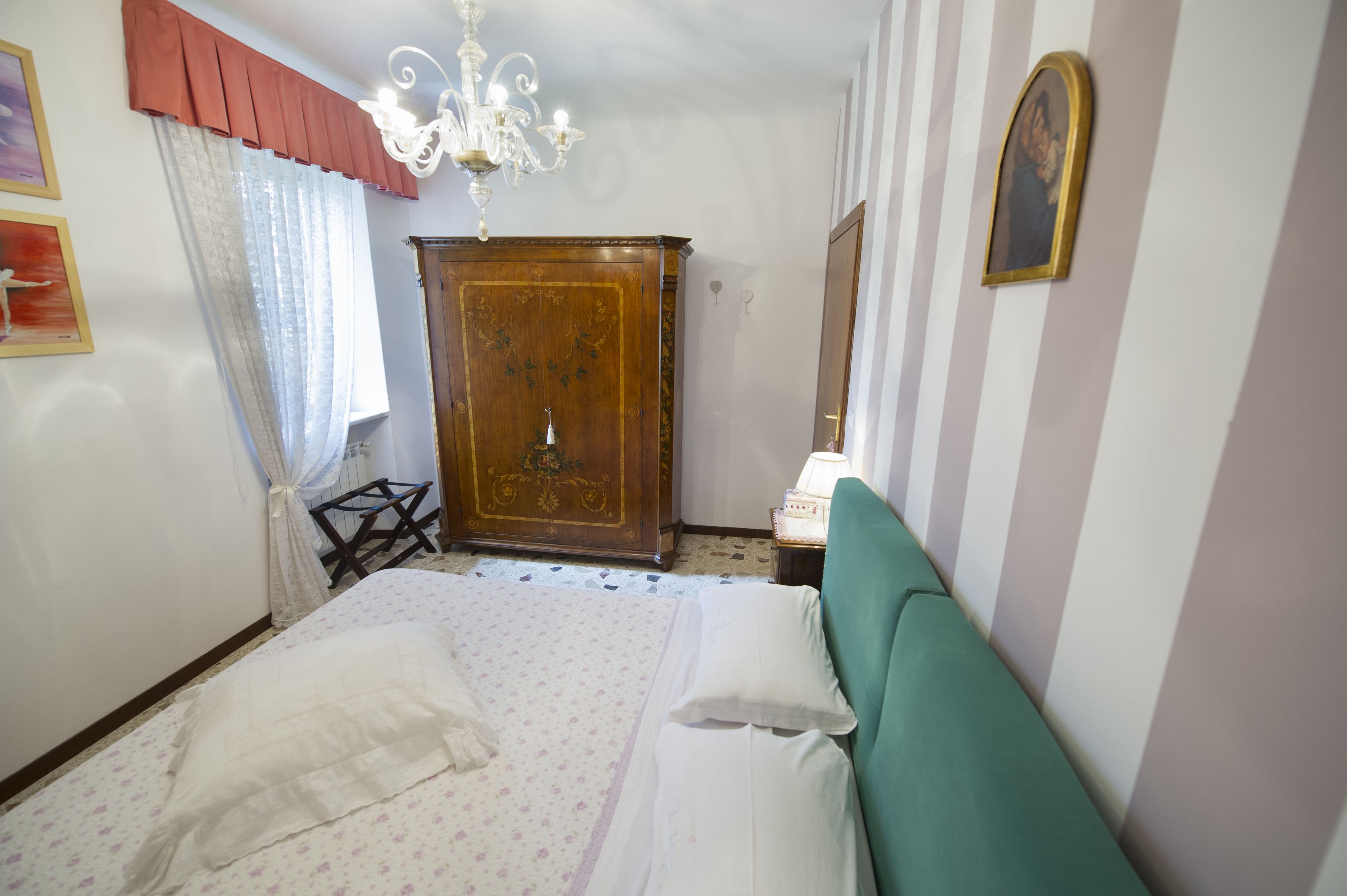 Une chambre à coucher avec un lit, une armoire en bois, un lustre et un miroir au mur.